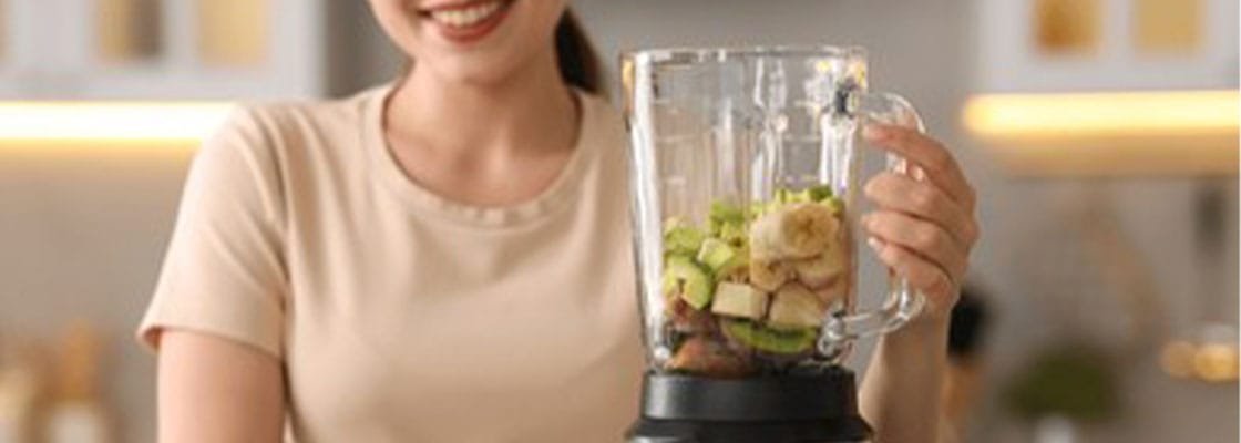 Woman making delicious smoothie with blender