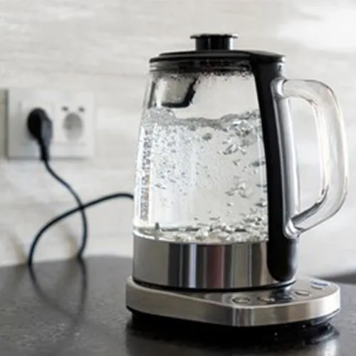 Transparent electric kettle with boiling water on table in the ki