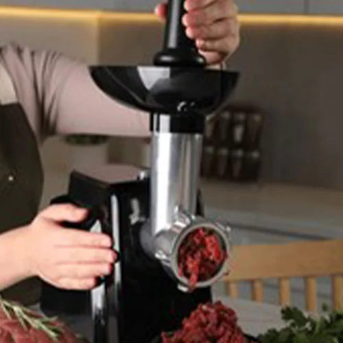 Woman making beef mince with electric meat grinder at white marbl